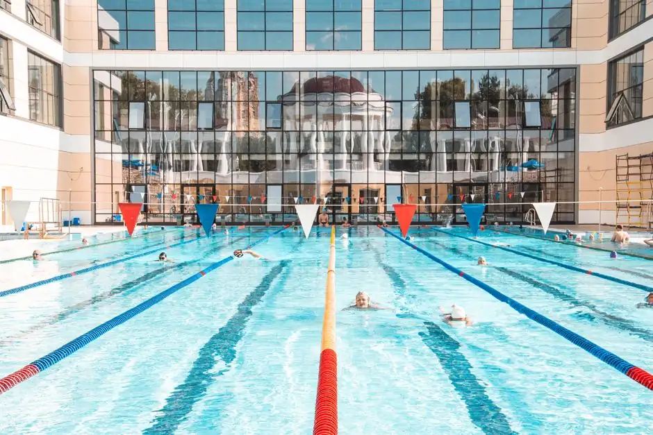 Vibrant swimming pool scene with clear reflections on a building facade, capturing leisure and activity.